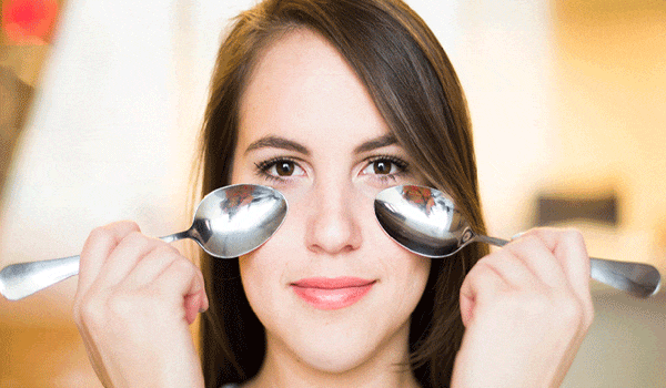 Reduce eye puffiness using two spoons